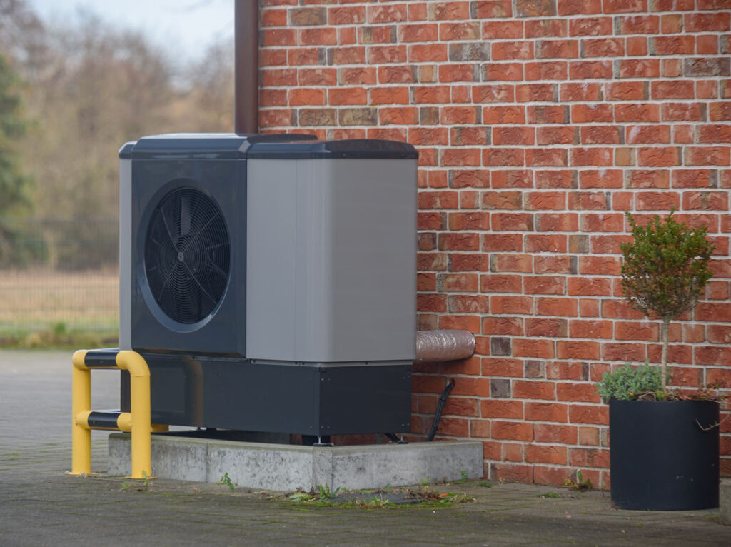 External commercial air source heat pump unit mounted beside building wall