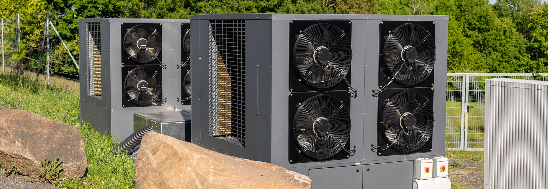 Large commercial air source heat pump system with multiple fans installed outside a commercial facility