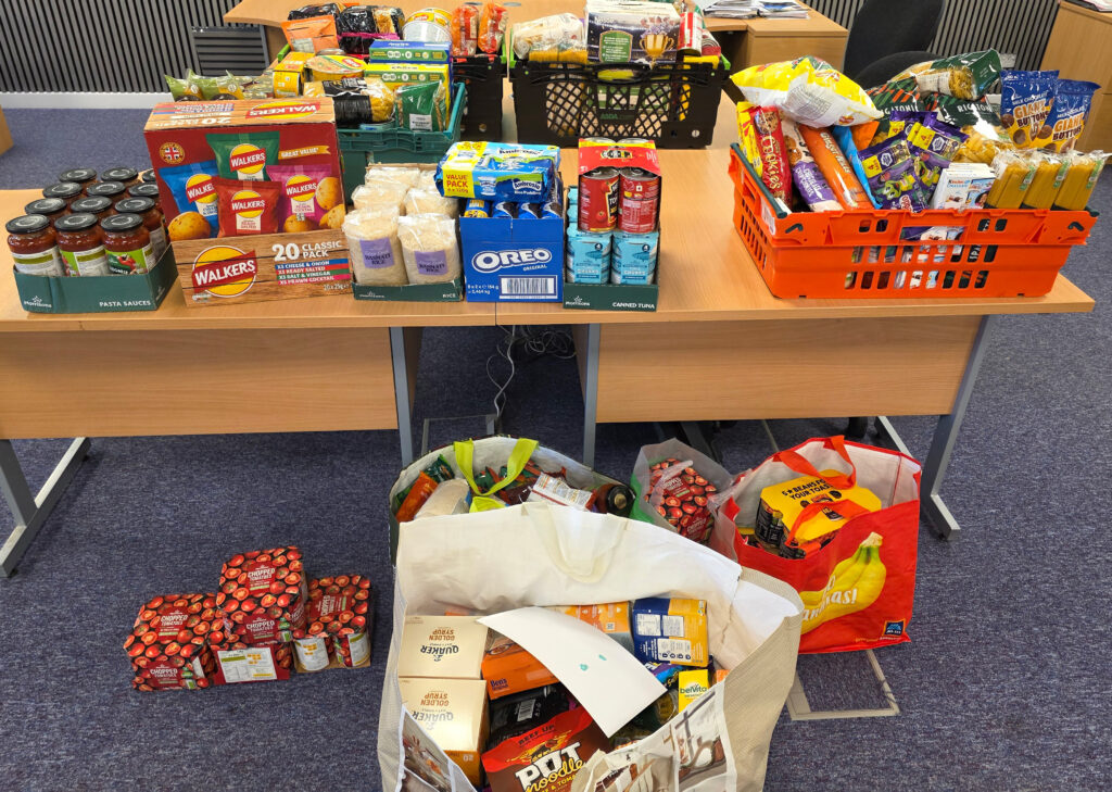Large collection of MK Food Bank donations from Crown Business Finance displayed across tables after crate collection