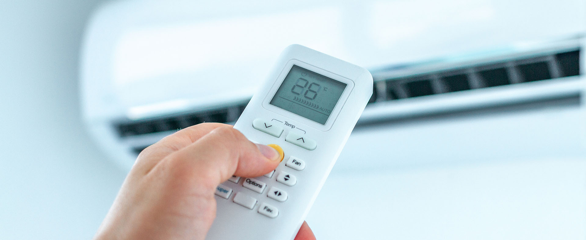 Hand adjusting remote control for domestic wall-mounted air conditioning system in a modern home in Milton Keynes