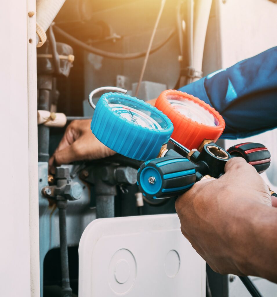 Engineer servicing commercial air conditioning equipment using diagnostic gauges