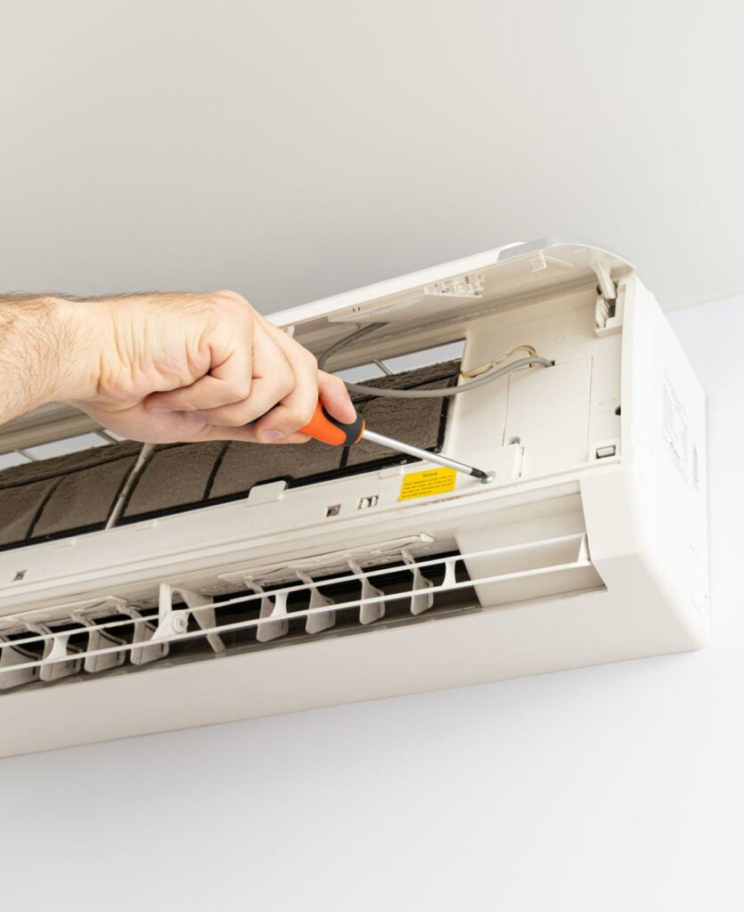 Engineer carrying out maintenance on a wall-mounted air conditioning unit