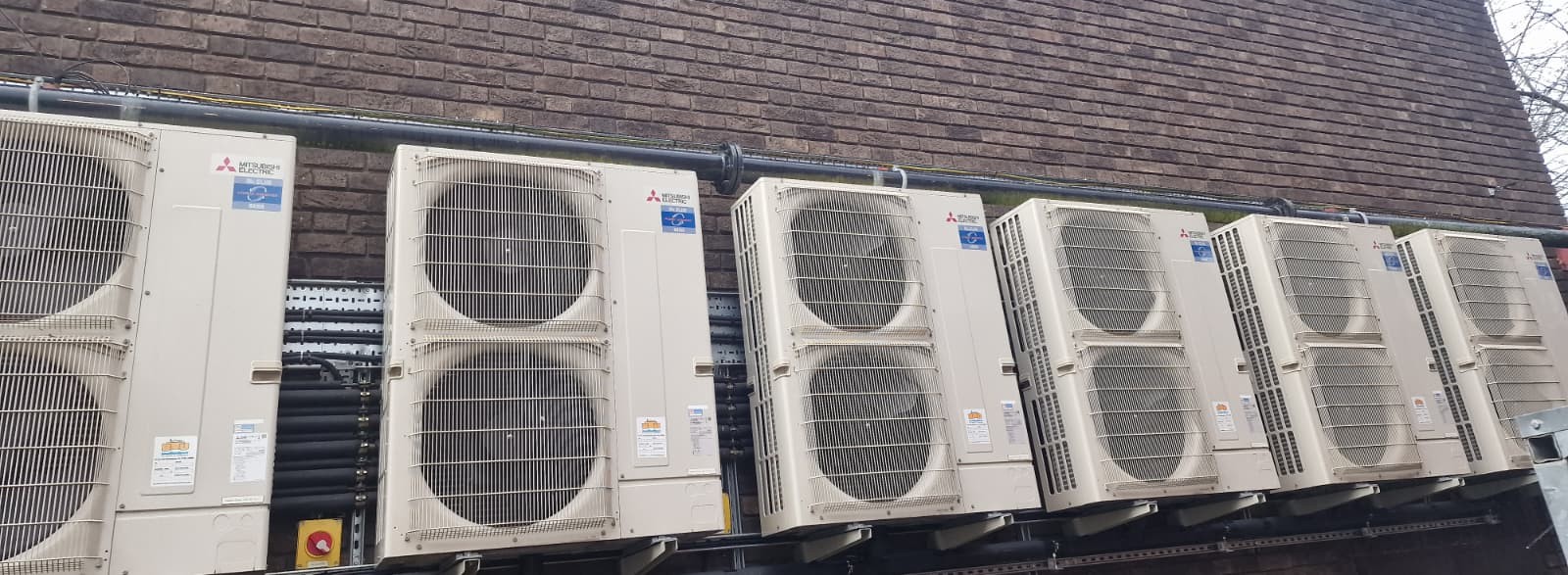 Row of Mitsubishi Electric outdoor air conditioning units mounted along a commercial building