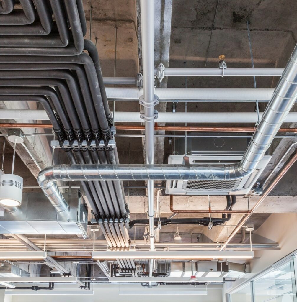 Exposed ventilation ductwork and a ceiling-mounted air conditioning unit in a commercial building
